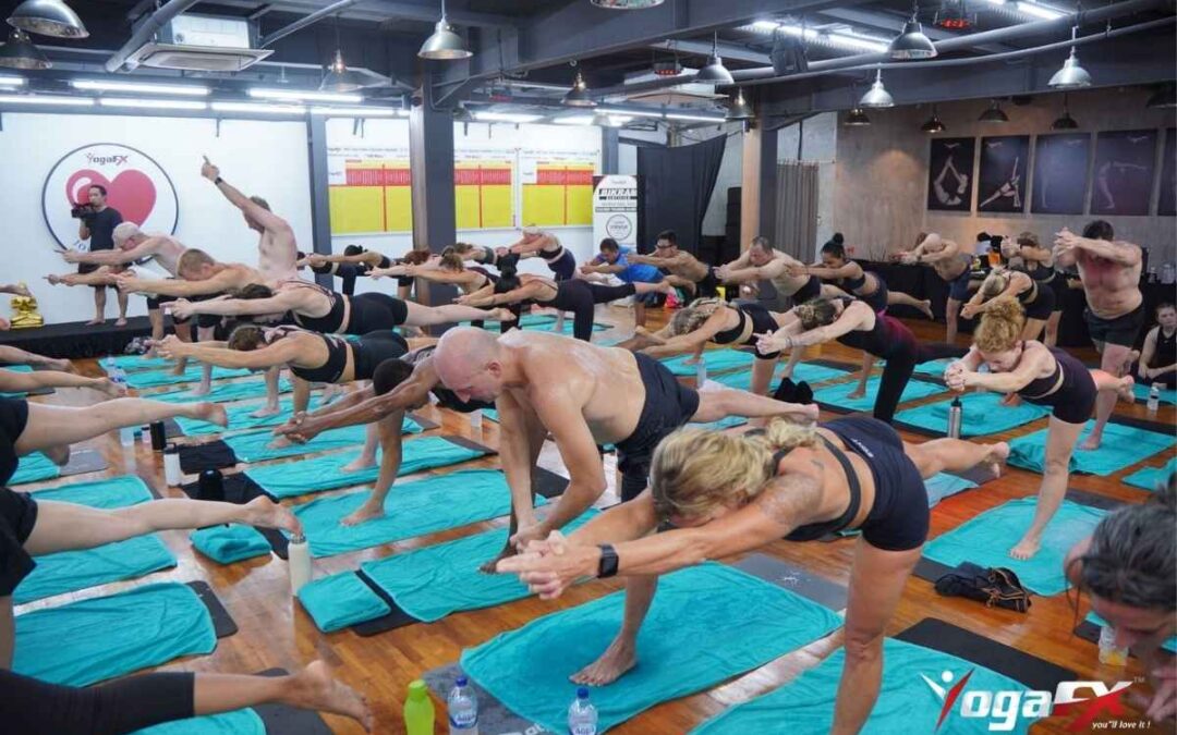 Large teacher training class holding Balancing Stick pose in a heated YogaFX studio in Bali