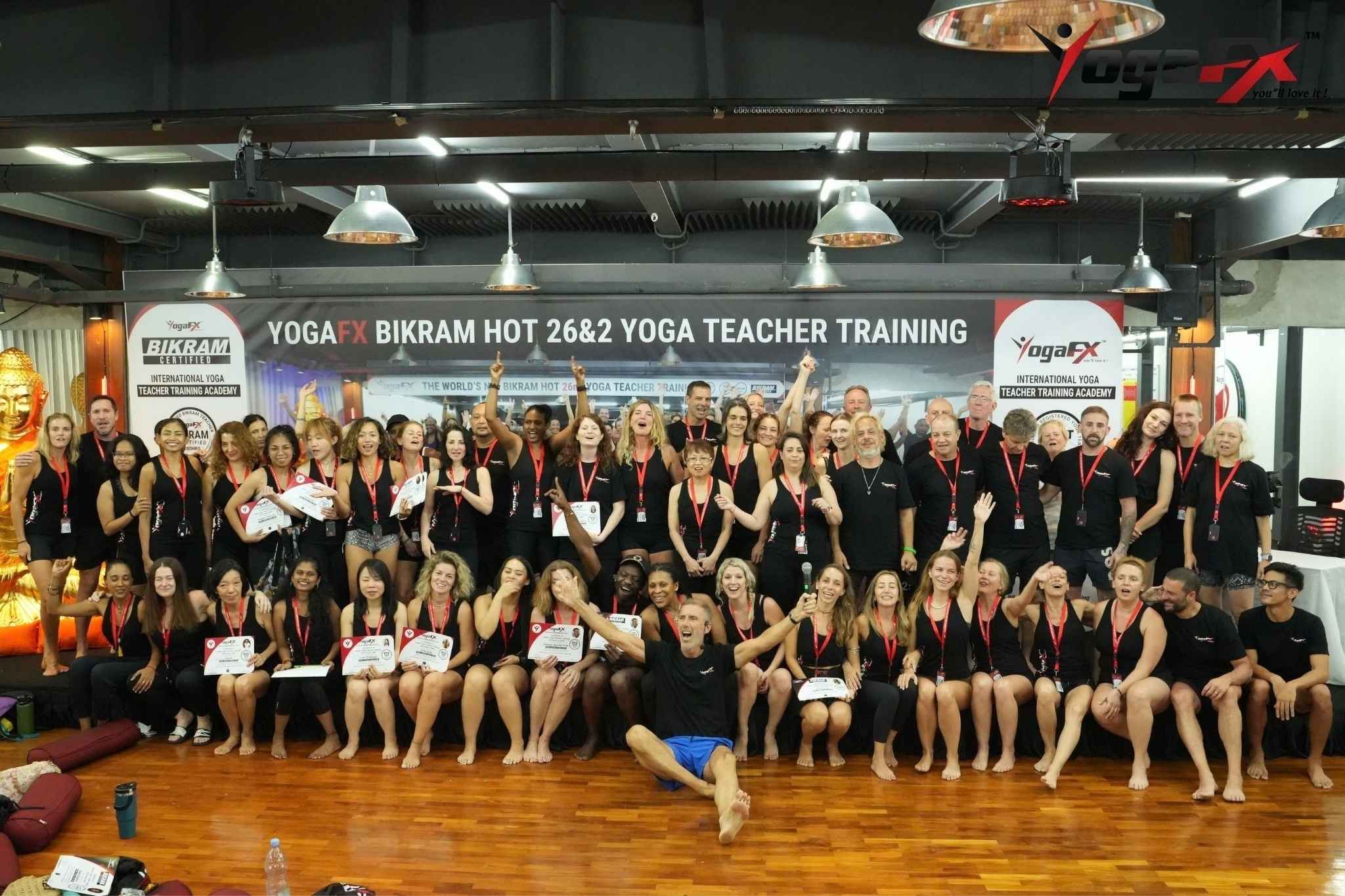 Graduating hot yoga teacher training group holding RYT 200 certificates after studying heat safety and the science of hot yoga