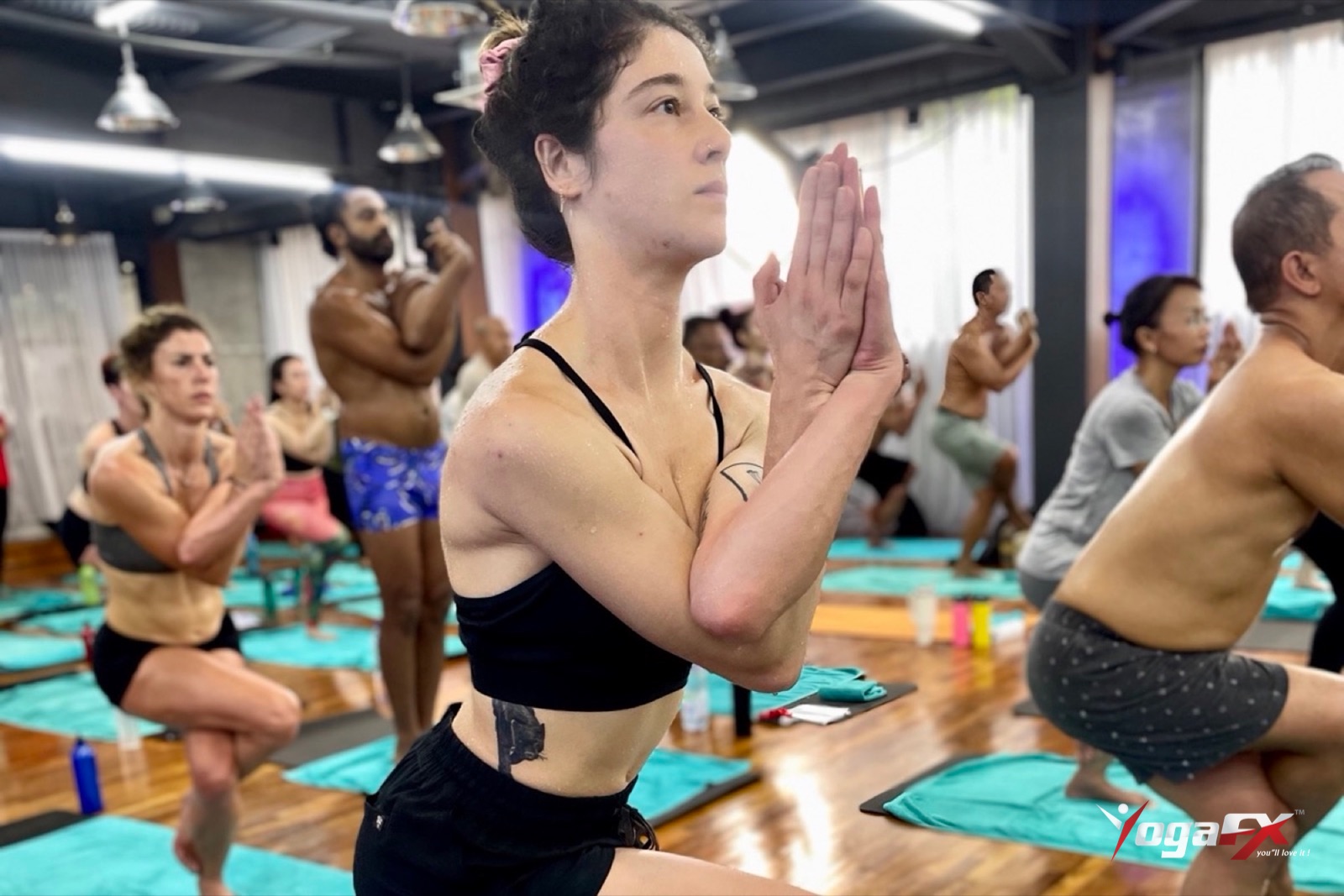 Student concentrating in eagle pose during a structured hot yoga class, a routine that supports hot yoga for depression research