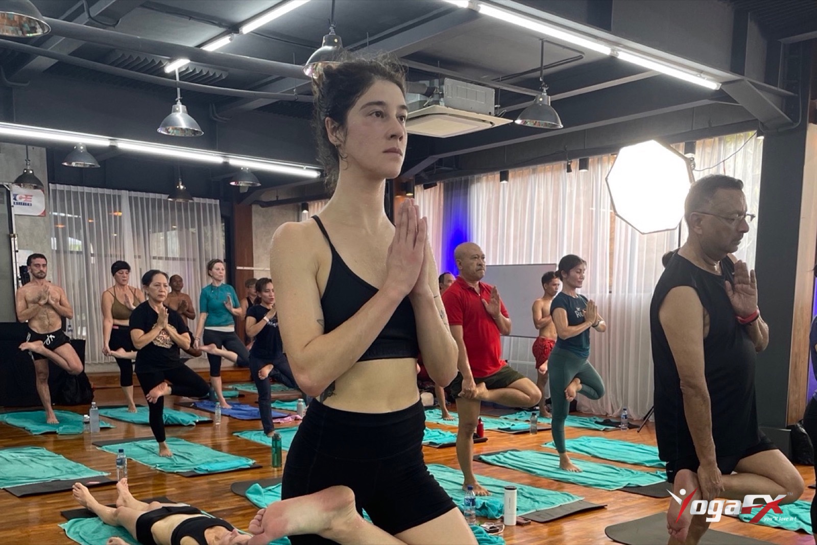 Students holding tree pose together in a heated studio, the kind of class studied in hot yoga for depression trials